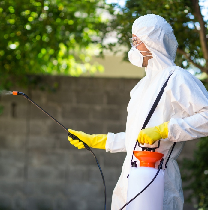 side view of worker wearing protective suit using pesticide in back yard